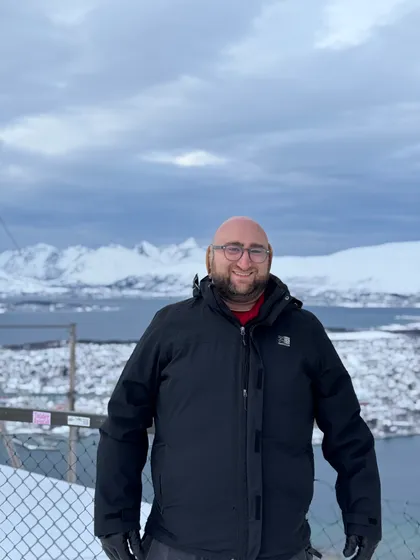 David Blumenau smiling outdoors in a snowy landscape.
